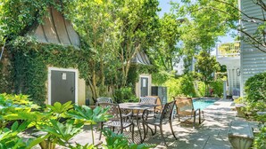 A patio with a pool, surrounded by lush greenery and a covered seating area. - Bright & Secluded Apartment with Pool Access (Charleston)