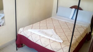 A neatly made bed with a patterned bedspread and a white towel. - Serena Hotel (Nakuru)