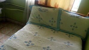 Una cama con un colcha de estampado floral y una almohada con el nombre de un hotel.