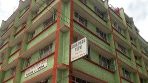 Un hotel de varios pisos con balcones y carteles que indican servicios como 'Shik Park View Hotel' y 'Boarding & Lodging'.