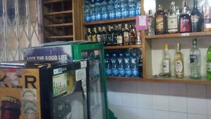Un área de bar con estantes llenos de bebidas embotelladas y un refrigerador.