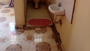 A small, narrow bathroom with a toilet, sink, and tiled floor. - Silver Rado West Lodge (Nakuru)