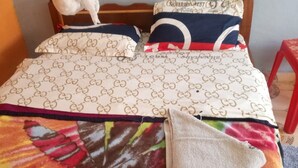 A bed with a colorful blanket and a pillow with a pattern. - Silver Rado West Lodge (Nakuru)