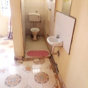 A small bathroom with a toilet, sink, and a red mat on the floor.
