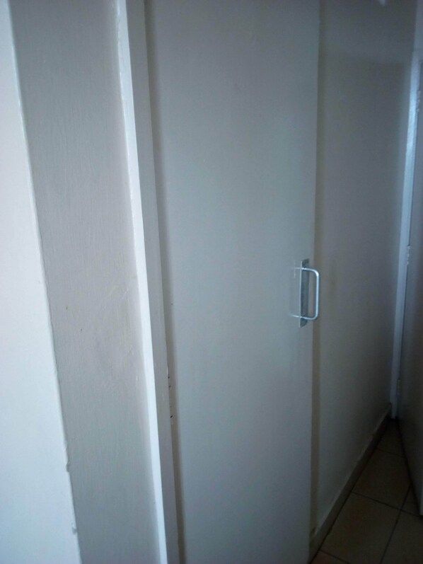 A narrow hallway with a white door featuring a silver handle. - Starwood Hotel Kagio (Kagio)
