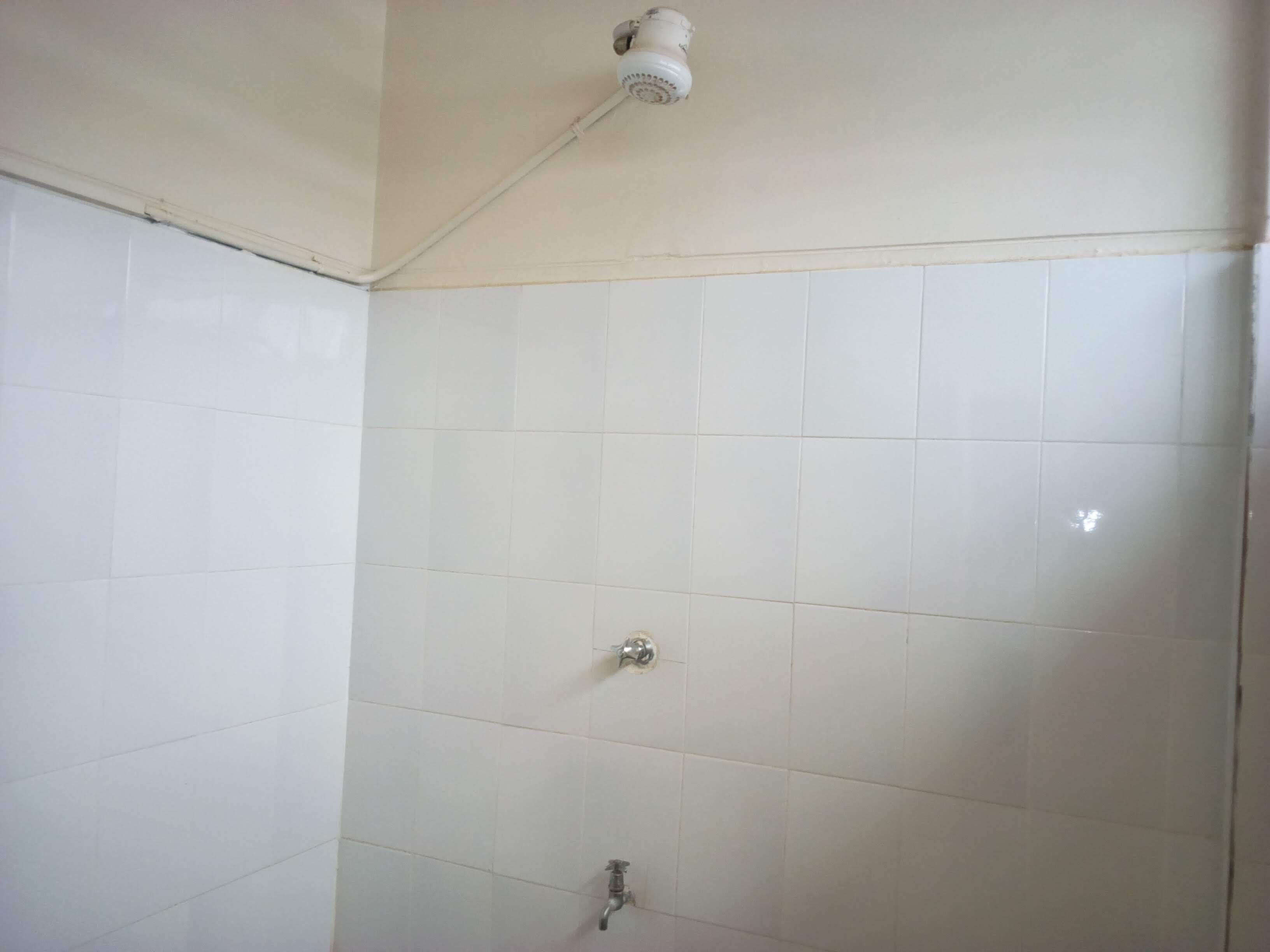 A bathroom with white tiled walls and a shower area.