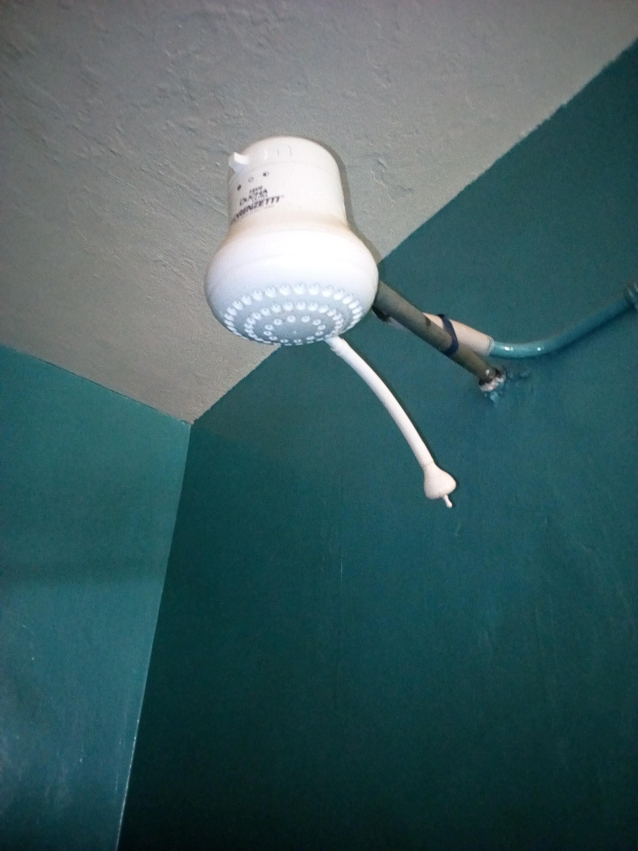 Ein weißer Duschkopf mit flexiblem Schlauch, der an der Wand befestigt ist.