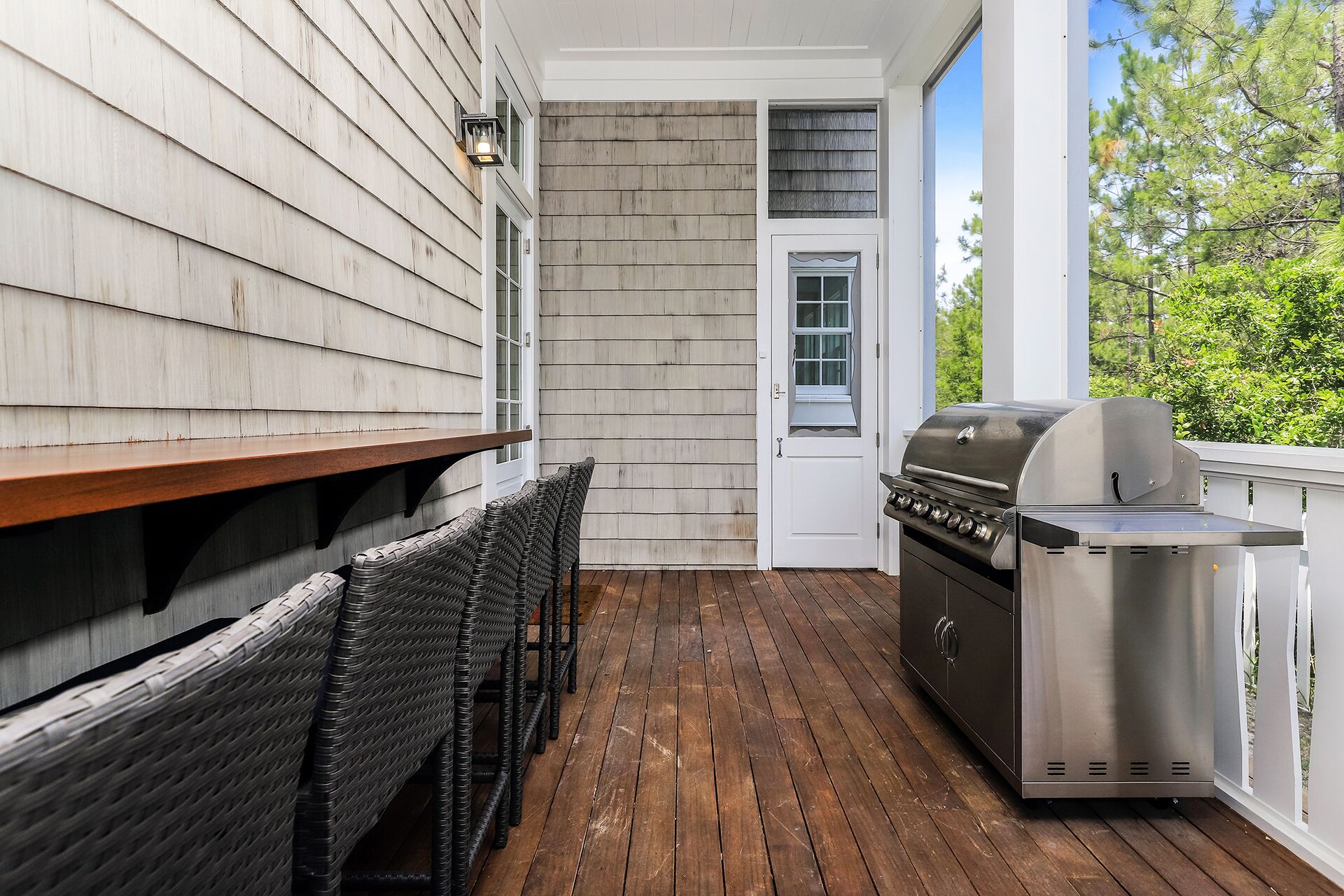 Un espace extérieur abrité, doté d’une terrasse en bois, d’un barbecue et d’un banc.