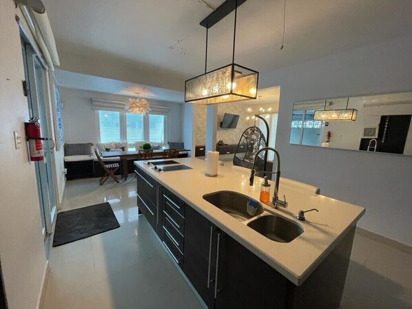 A modern kitchen with a central island, double sinks, and a pendant light.