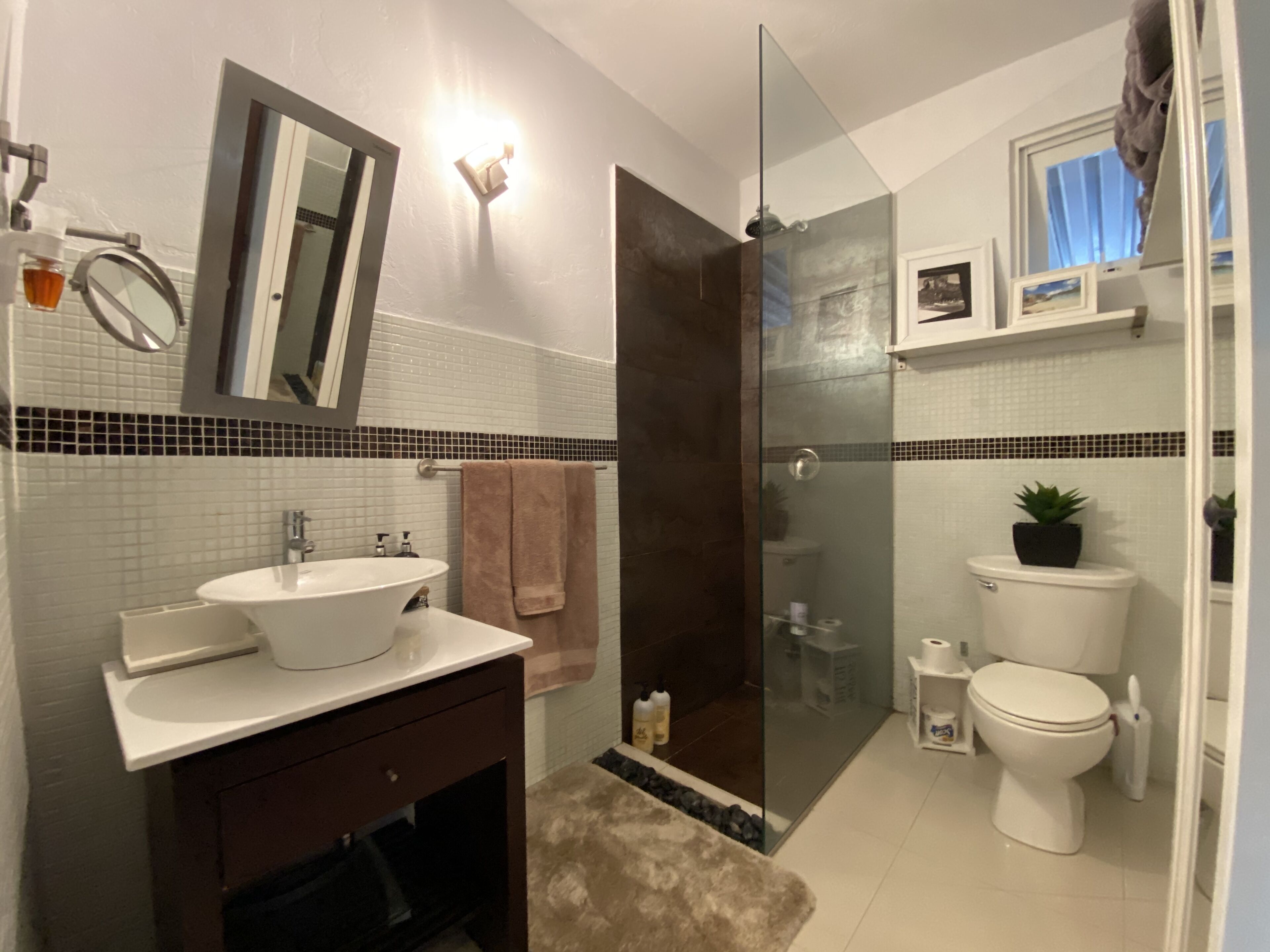 Een moderne badkamer met een douchecabine van glas, een wit wastafelmeubel en een toilet.