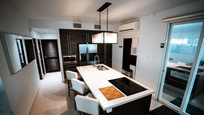 Una cocina moderna con una isla central, taburetes de bar blancos y un ventanal amplio.