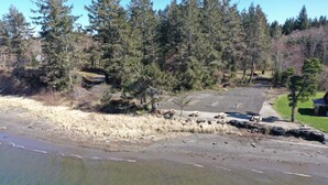 A beach with a parking area and a building in the background.