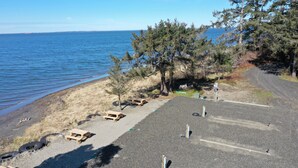 A parking area with picnic tables and a view of the sea. - Exclusive Bayside RV Site #4 (Aberdeen)