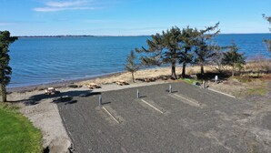 A parking area with a view of a calm body of water and a distant shoreline. - Exclusive Bayside RV Site #4 (Aberdeen)