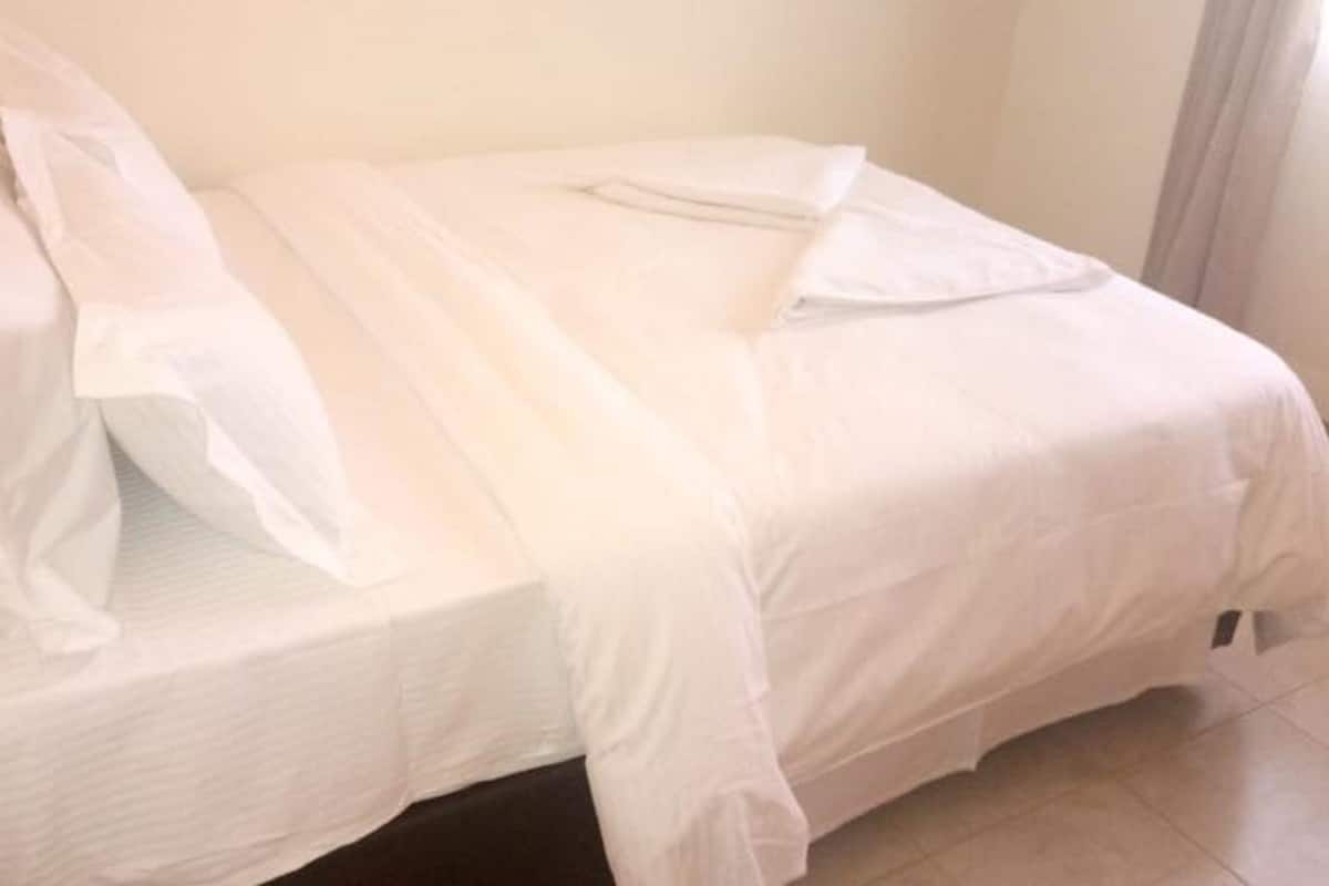 A bed with white linens and a pillow.