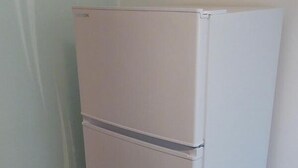A white, two-door refrigerator in a corner of a room with tiled flooring. - Apartment Jungle Adventure (Günzburg)