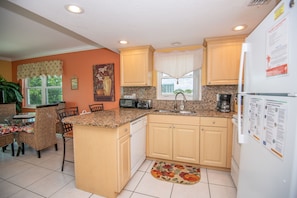 Compact kitchen with central island, dining table, and refrigerator, offering a convenient space for meal preparation and dining.