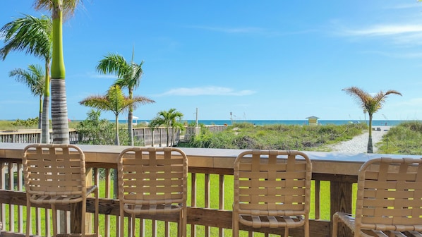 A wooden deck with chairs overlooking a beach.