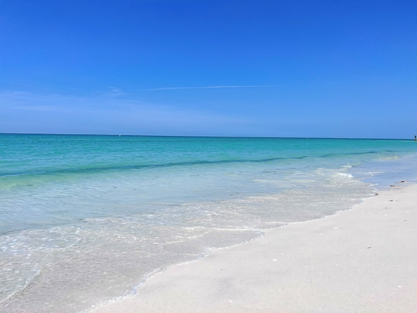 Enjoy a serene beach experience with clear waters gently lapping onto the sandy shore.