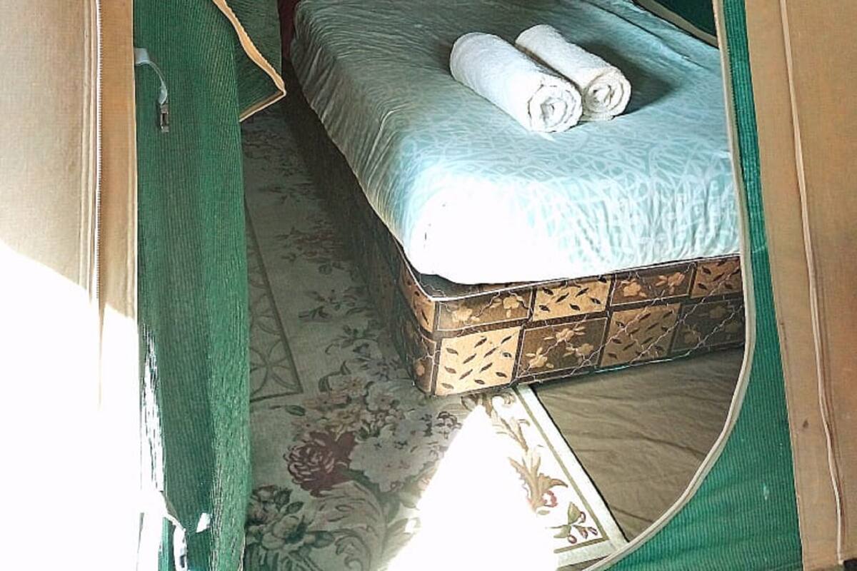 Una carpa con una cama, almohadas y toallas enrolladas.