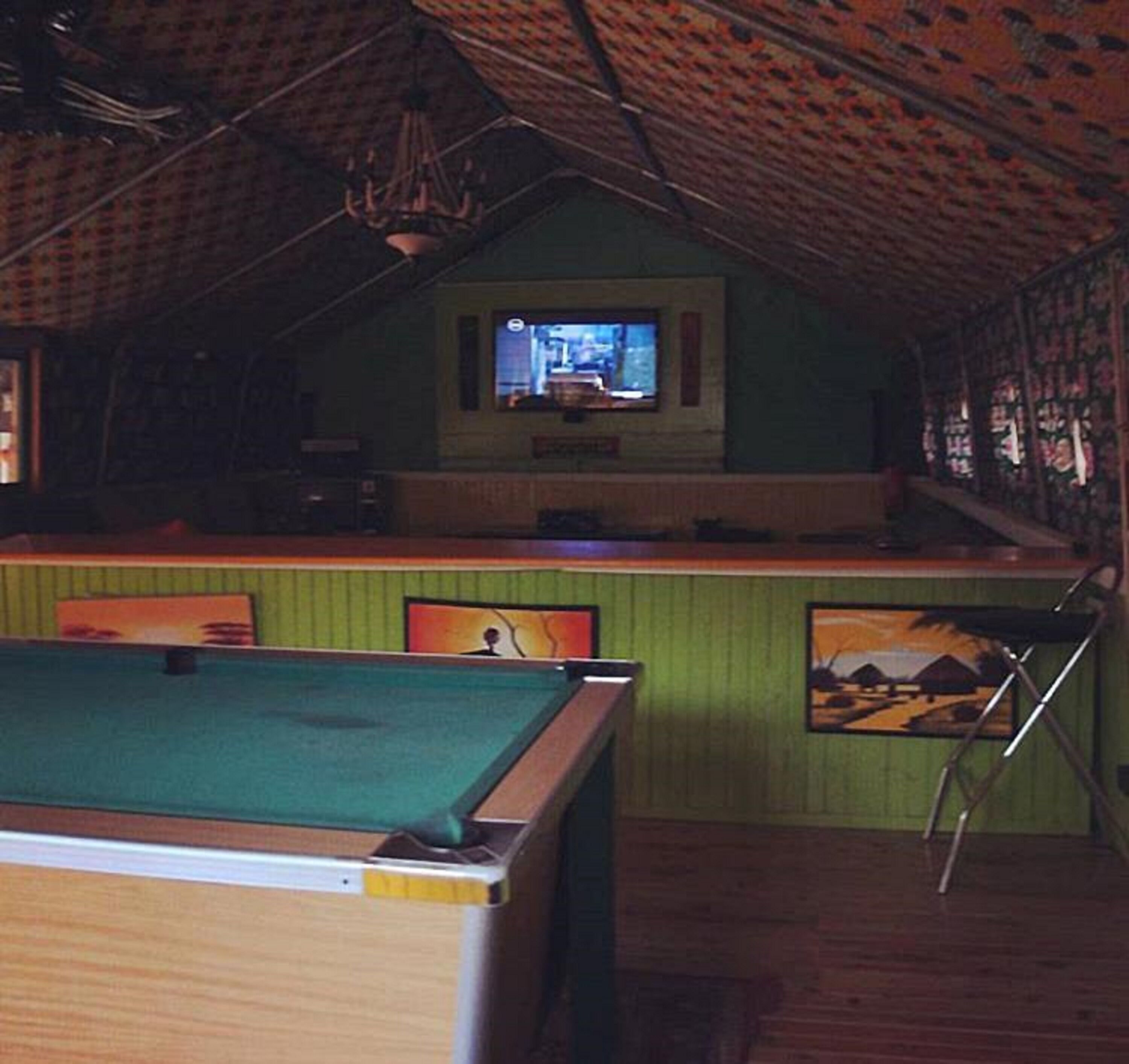 Una habitación con mesa de billar, zona de bar y pantalla de televisión.