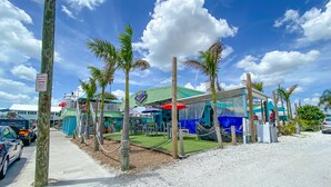 A beachside restaurant with outdoor seating, palm trees, and a no parking sign.