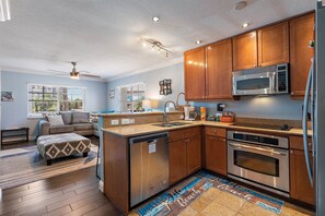 Enjoy cooking in this kitchen with a central island, dishwasher, microwave, and oven, complemented by a large window with an outdoor view.