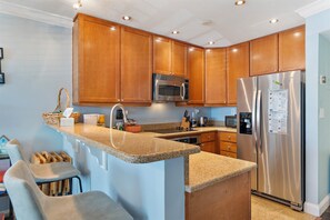 Enjoy cooking in this well-equipped kitchen with a central island, stainless steel appliances, and ample workspace.