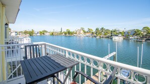A balcony with a view of a calm river, docked boats, and a distant cityscape. - Cozy Waterfront Condo | Patio & Beach Access (St. Pete Beach)
