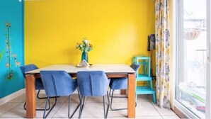 A dining area with a yellow wall, a wooden table, and blue chairs.