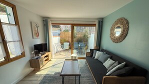 Una sala de estar con sofá, televisión y una mesa de comedor.