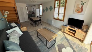 Una sala de estar con sofá, mesa de centro, televisor y un comedor con sillas y una mesa.