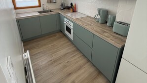 Una cocina moderna con horno empotrado, microondas y una ventana con cortinas.