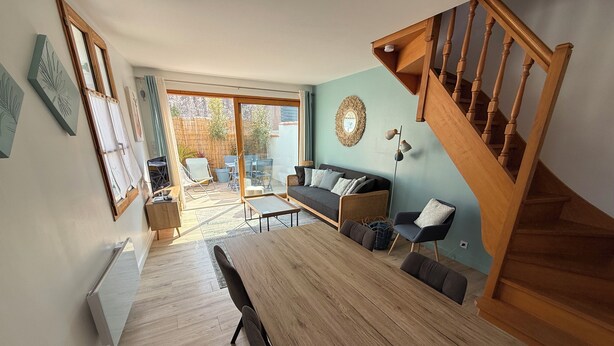 Amplia sala de estar con una mesa de comedor de madera, un sofá y una escalera.