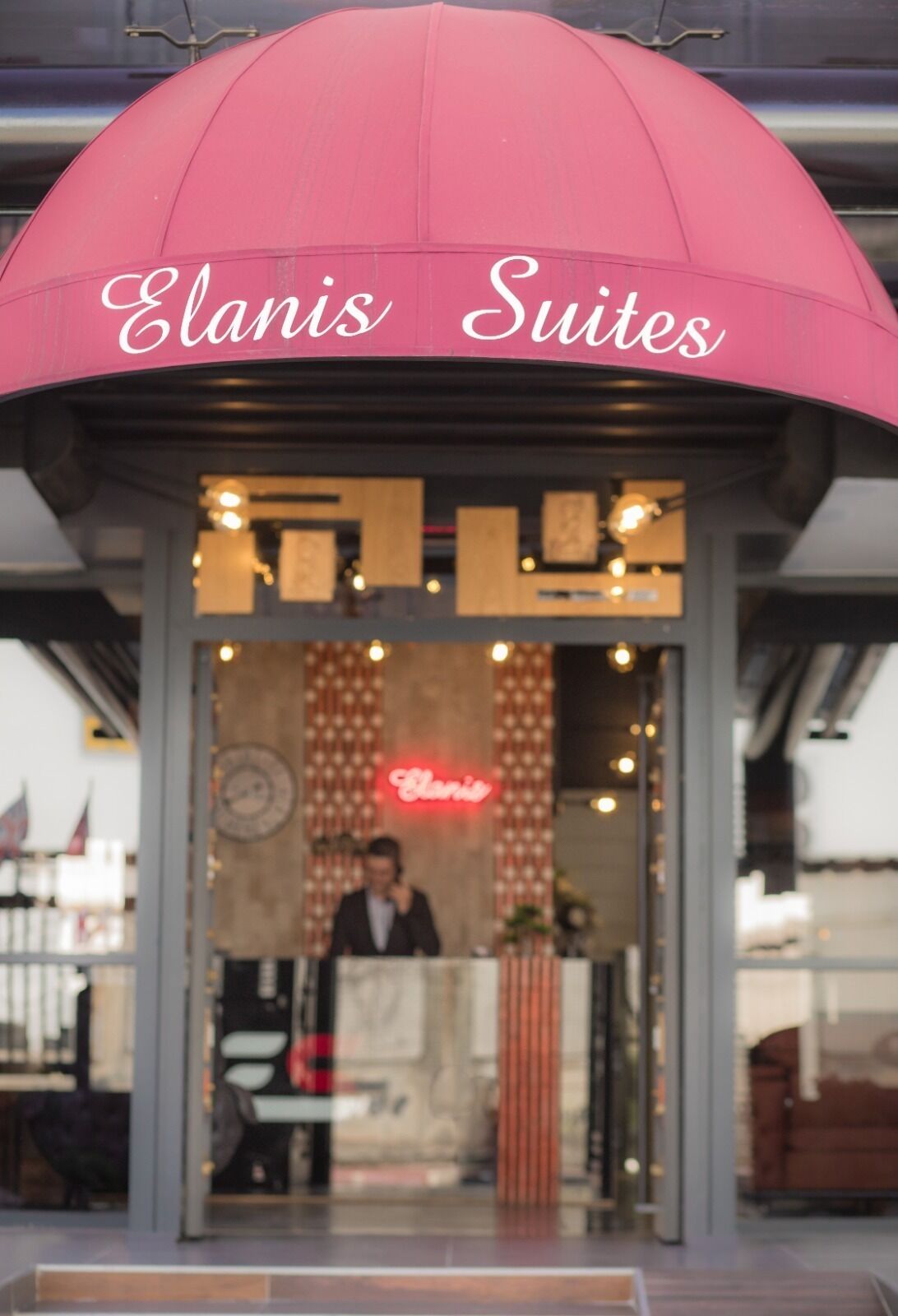 A hotel entrance with a pink awning labeled "Elanis Suites".
