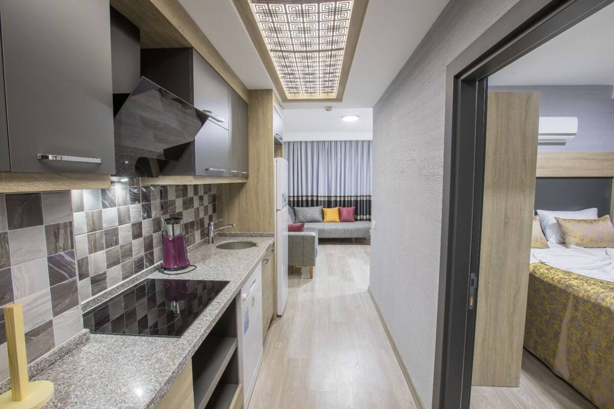 A modern hotel room with a kitchenette, a sofa, and a bed.