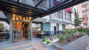 A modern building with a glass entrance, outdoor seating area, and a landscaped garden.