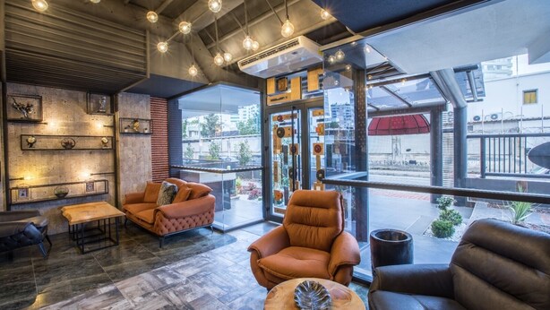 A modern interior with leather sofas, a wooden coffee table, and a large window offering a view of the street.