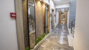 A modern hallway with a polished stone floor, a glass railing, and a staircase with metal railings.