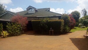 A house with a paved driveway, a garage, and a well-maintained garden with various plants and shrubs. - Senior Chief Wambugu Palace (Marua)