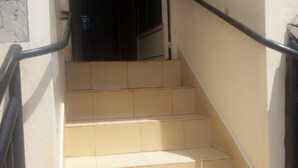 A set of beige tiled stairs with black handrails, leading to a dark doorway. - Senior Chief Wambugu Palace (Marua)