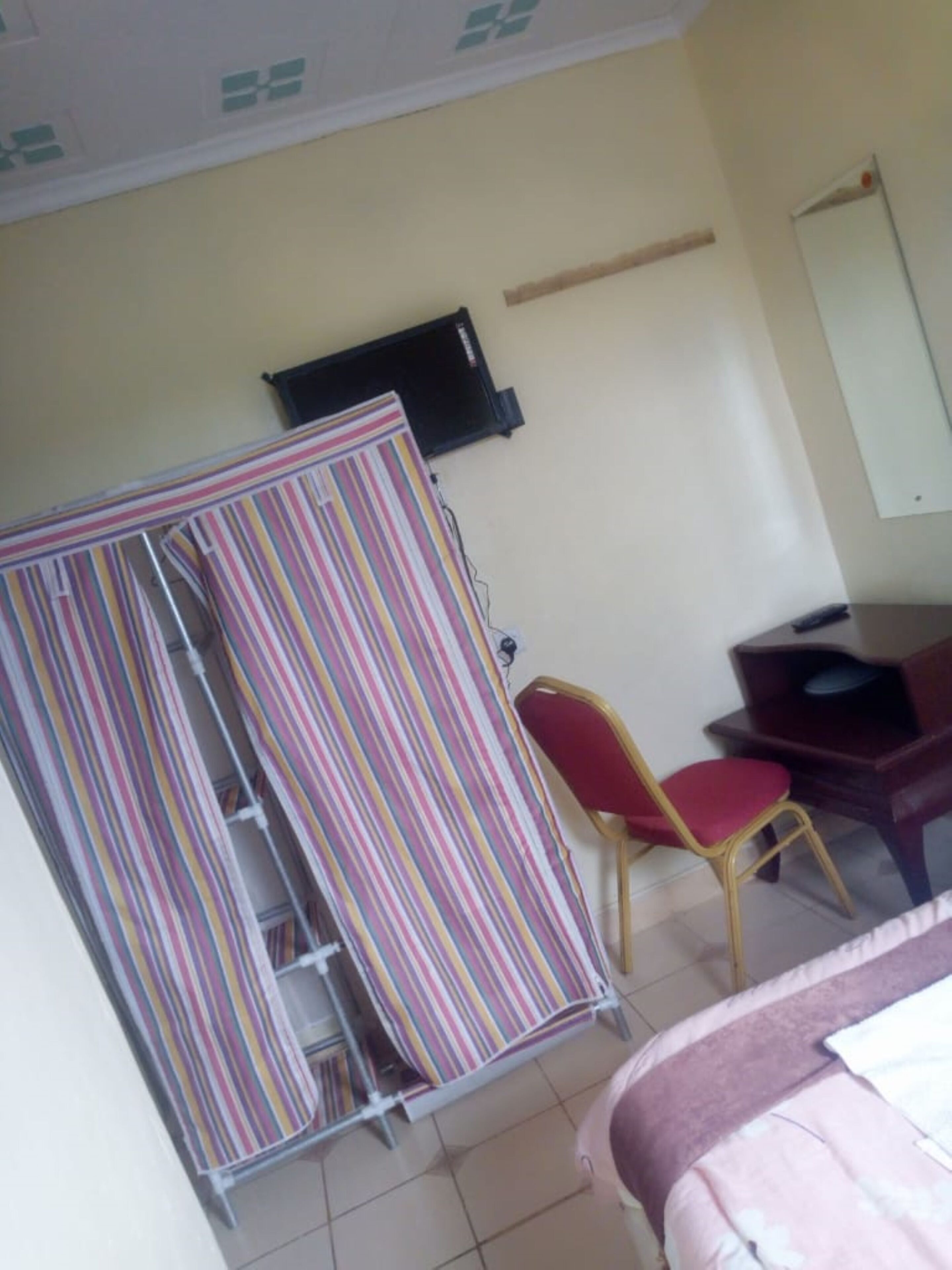 A hotel room with a bed, a desk, a chair, and a striped curtain.