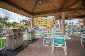 An outdoor patio with a grill, chairs, and tables.
