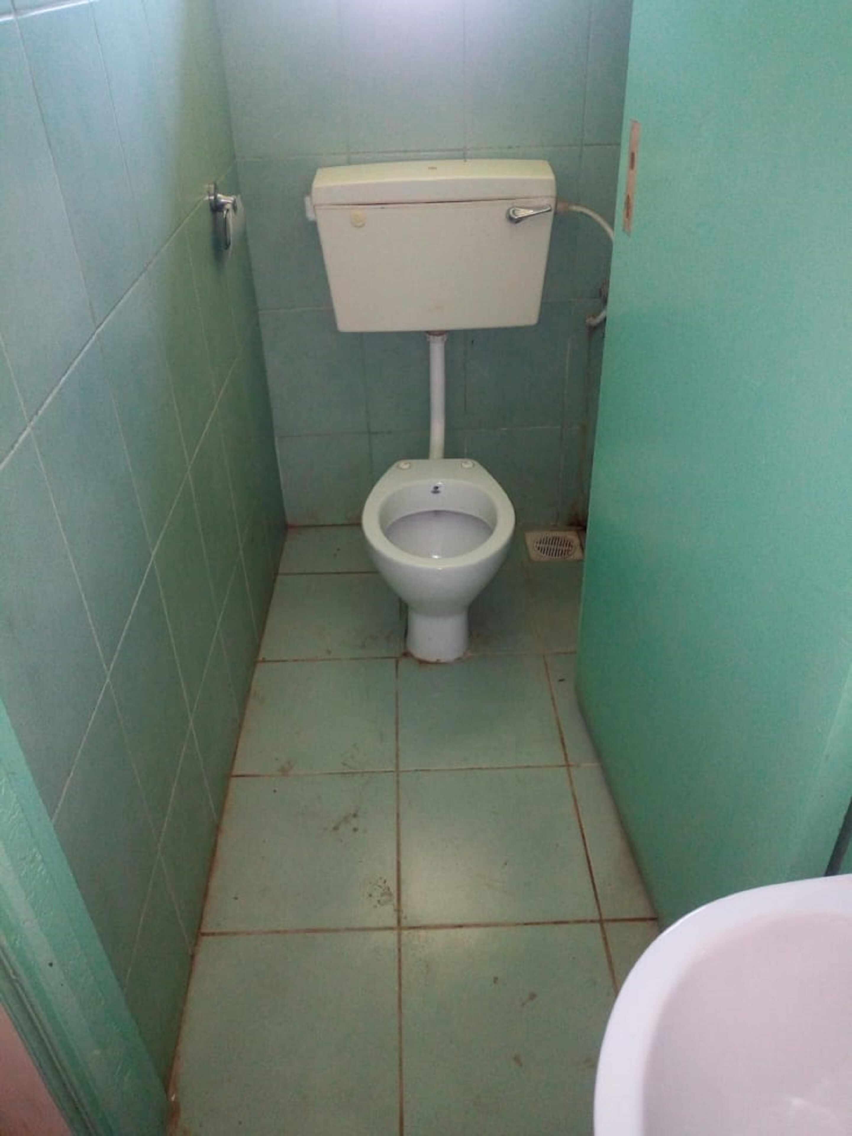 Ein kleines, schmales Badezimmer mit Toilette und Waschbecken.