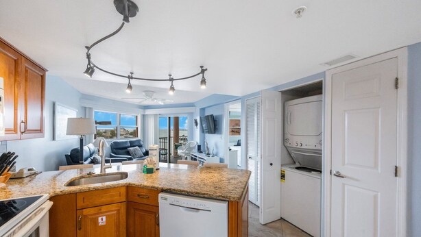 A modern kitchen with granite countertops, wooden cabinets, a built-in dishwasher, and a large island. - Coastal Getaway | Resort Amenities (St. Pete Beach)
