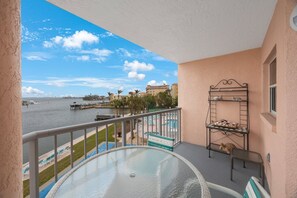 A balcony with a view of a marina, a pool, and a building across the water. - Resort Retreat | Steps to Beach (St. Pete Beach)