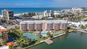 A hotel with multiple balconies, a swimming pool, and a view of the beach and ocean. - Coastal Getaway | Resort Amenities (St. Pete Beach)
