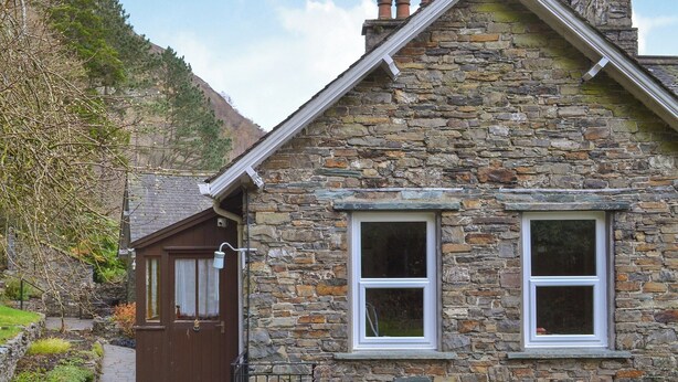 A stone house with a brown door, a small porch, and a window with a white frame. - Squirrel’s Retreat - UK30821 (Thornthwaite, near Keswick)