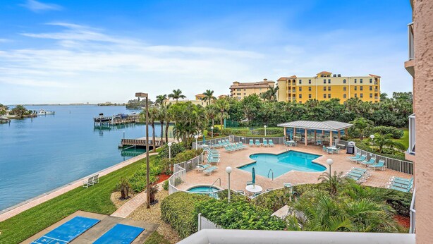 A resort with a large pool, lounge chairs, and a view of the water. - Luxury Coastal Getaway | Resort Perks (St. Pete Beach)
