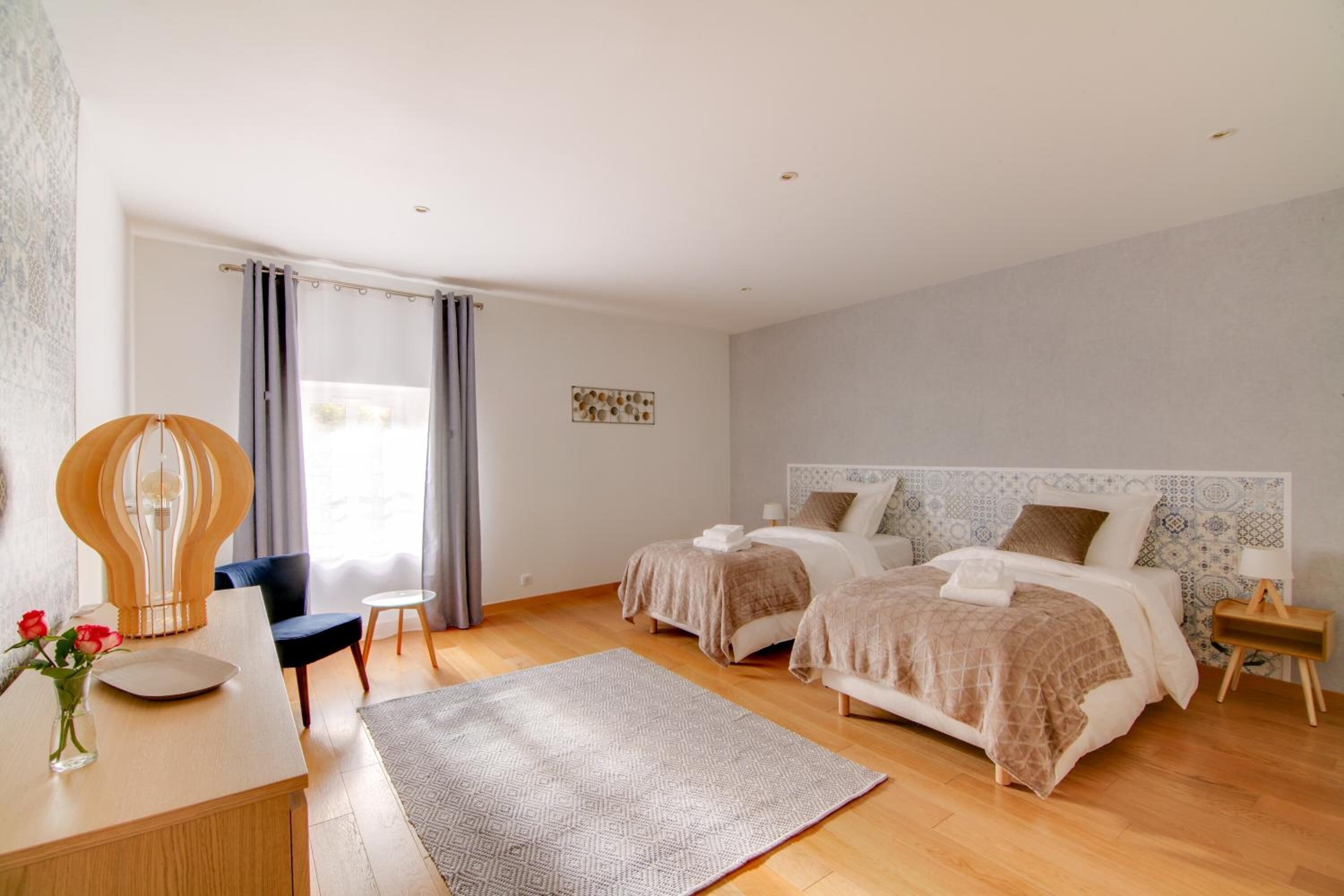 Una habitación de hotel moderna con dos camas, un escritorio, una silla y un ventanal con cortinas.